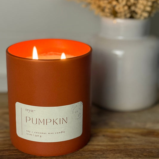 Candle labeled 'Pumpkin' with a label on a wooden surface.