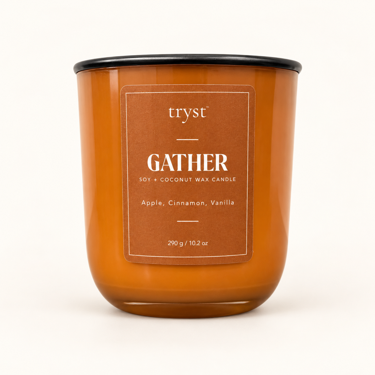 Gather soy and coconut wax candle in an orange glass jar with a black lid, labeled apple, cinnamon, vanilla